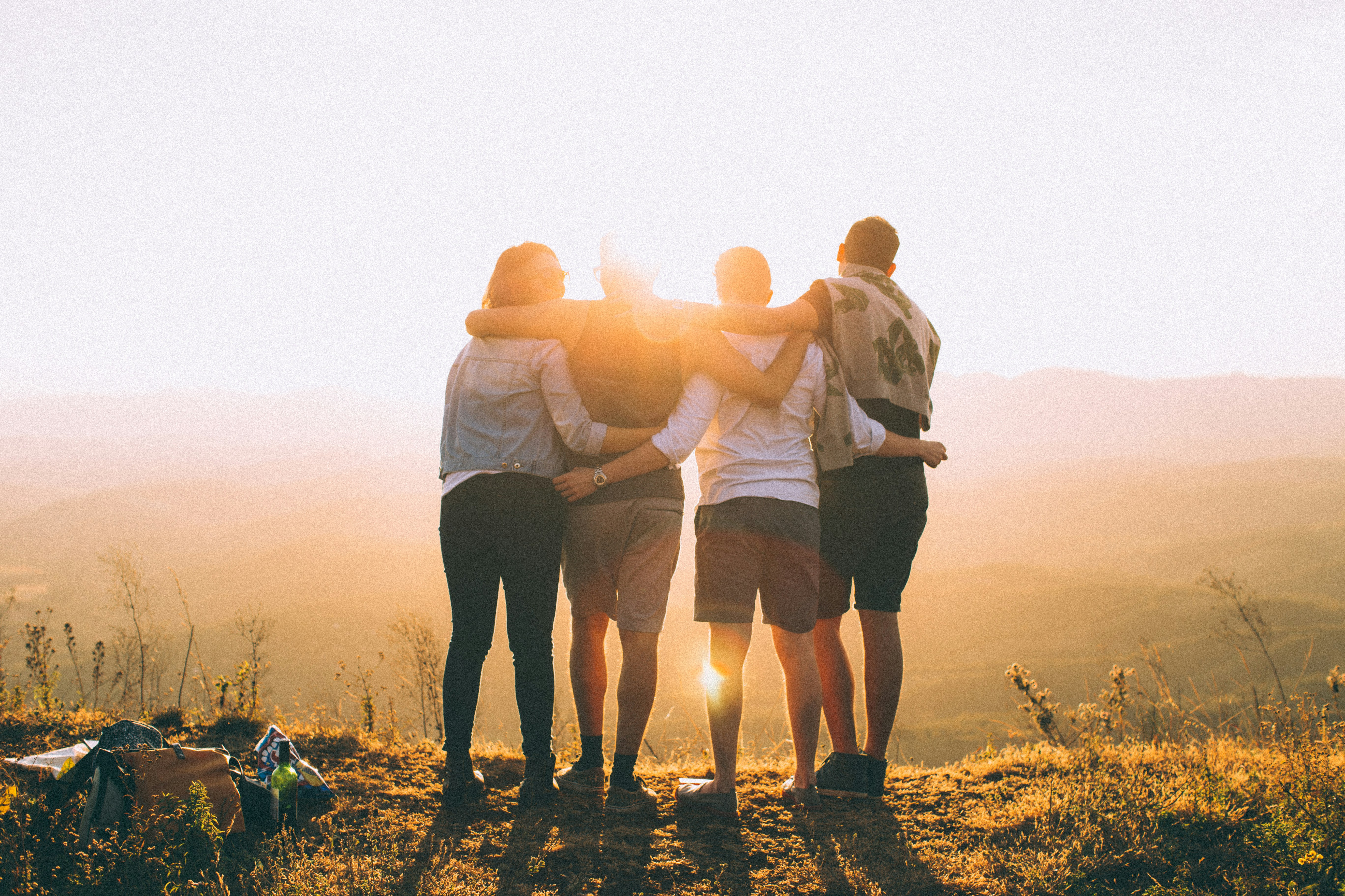 image of 4 people in silhouette in the sunset embracing one another (decorative)