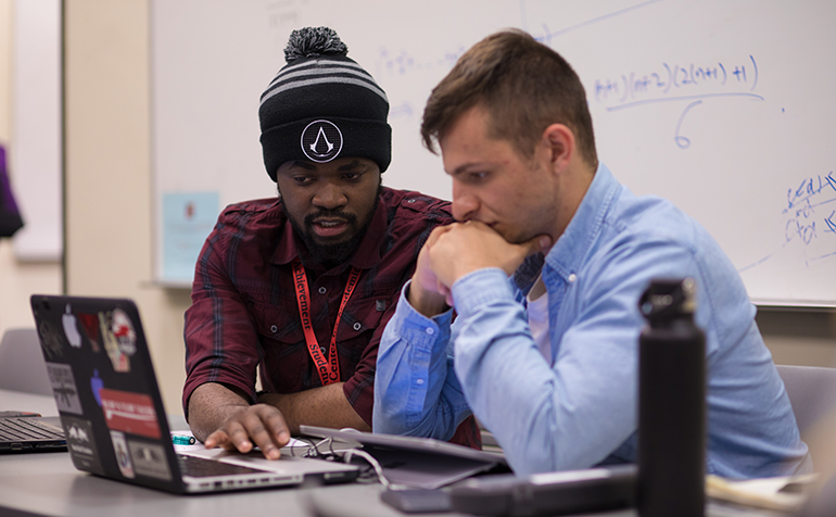 Two students work at laptop