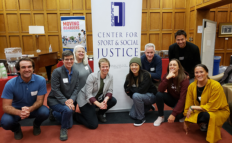 Faculty stand in front of CSSJ logo