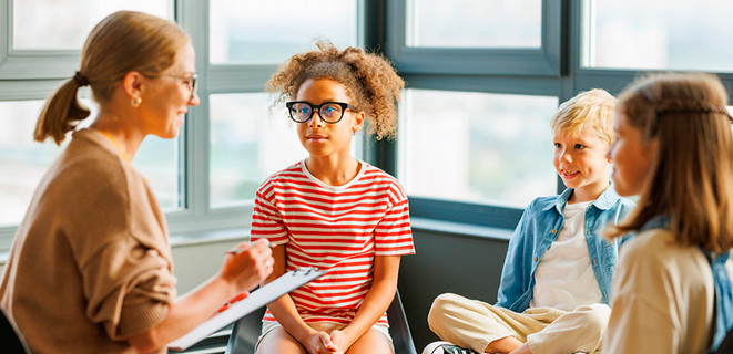 A school counselor with three children sitting together in a group session