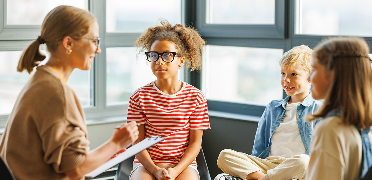 A school counselor with three children sitting together in a group session