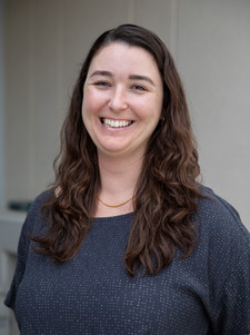 This is a photo of the SCAA Director Rachel against a grey stone wall.